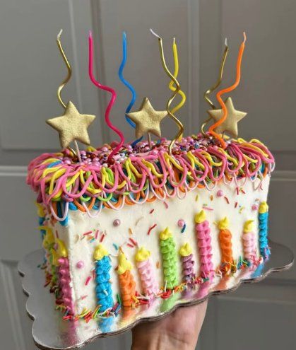 Bolo coberto de velas coloridas com bico de confeitar em arco-íris