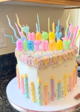 Bolo em tons pastel com velas e letras Happy Birthday