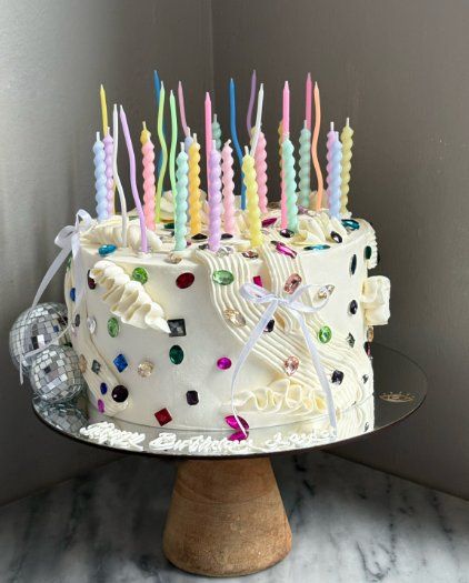 Bolo branco com velas pastel torcidas e aplicações coloridas