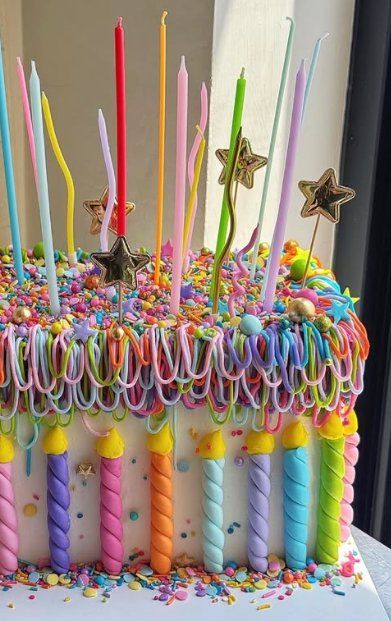 Bolo com dezenas de velas torcidas coloridas e confeitos