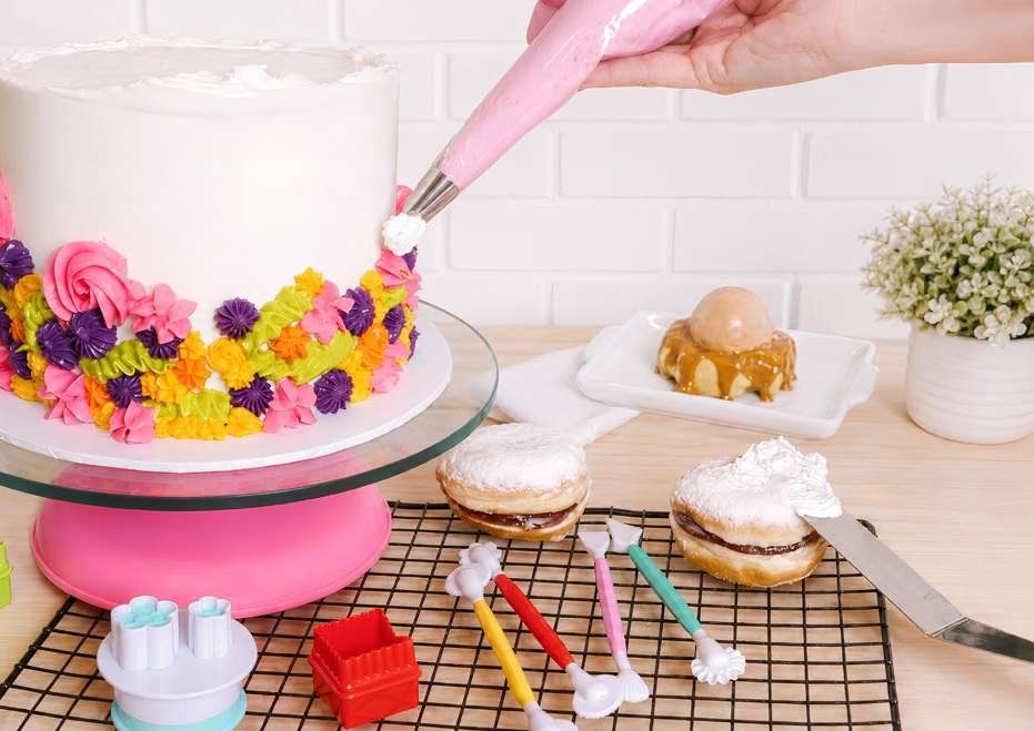 Confeiteira decorando bolo com bico de confeitar